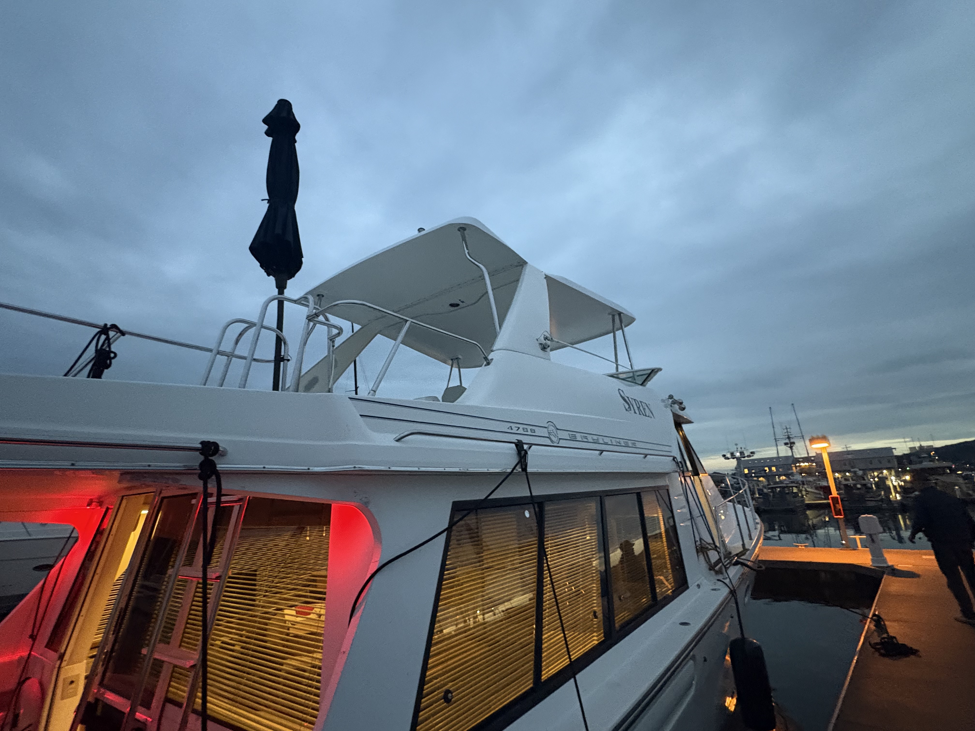 A Bayliner with an Essential Shipyard hardtop installed over the flybridge, at dusk