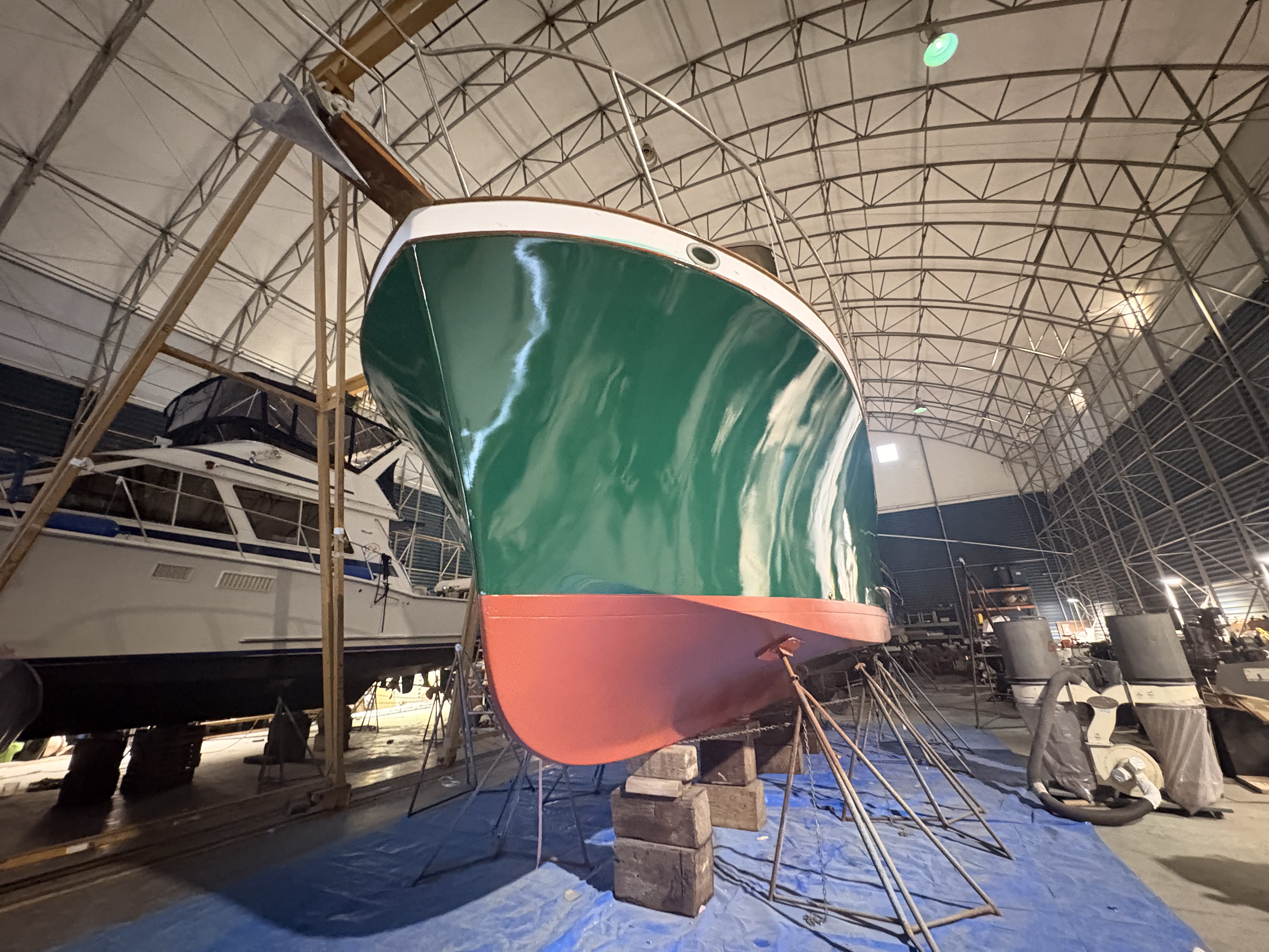 Fiberglass hull under repair in the covered bay, Essential Shipyard