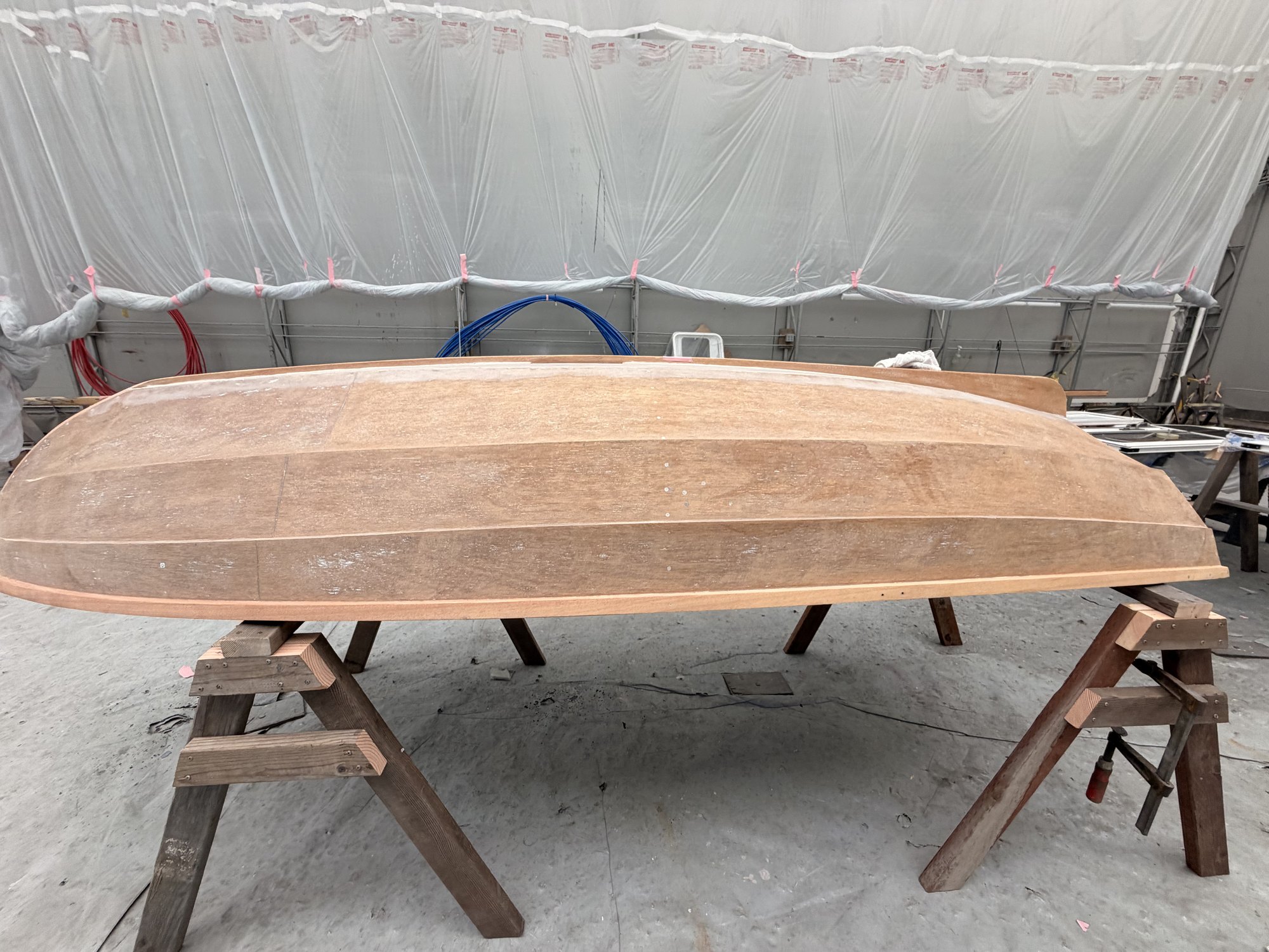 A small craft hull in bare timber on trestles before finishing.