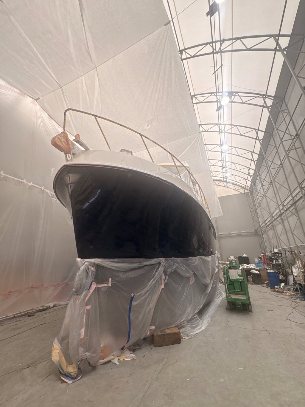 American Tug in the spray booth at Essential Shipyard, navy Awlcraft 2000 hull freshly sprayed, bottom masked
